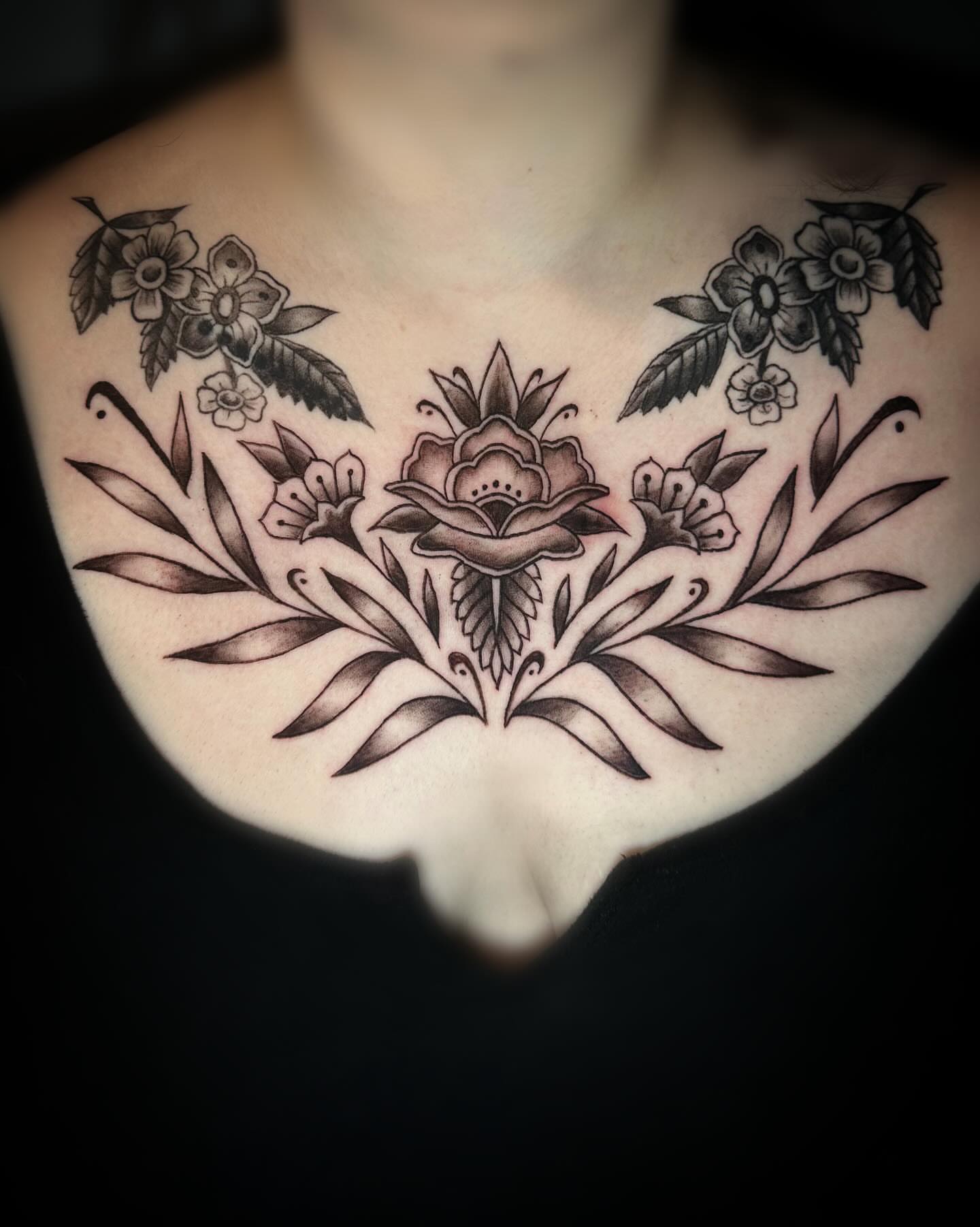 Floral arrangement black and grey tattoo on the chest by Saint