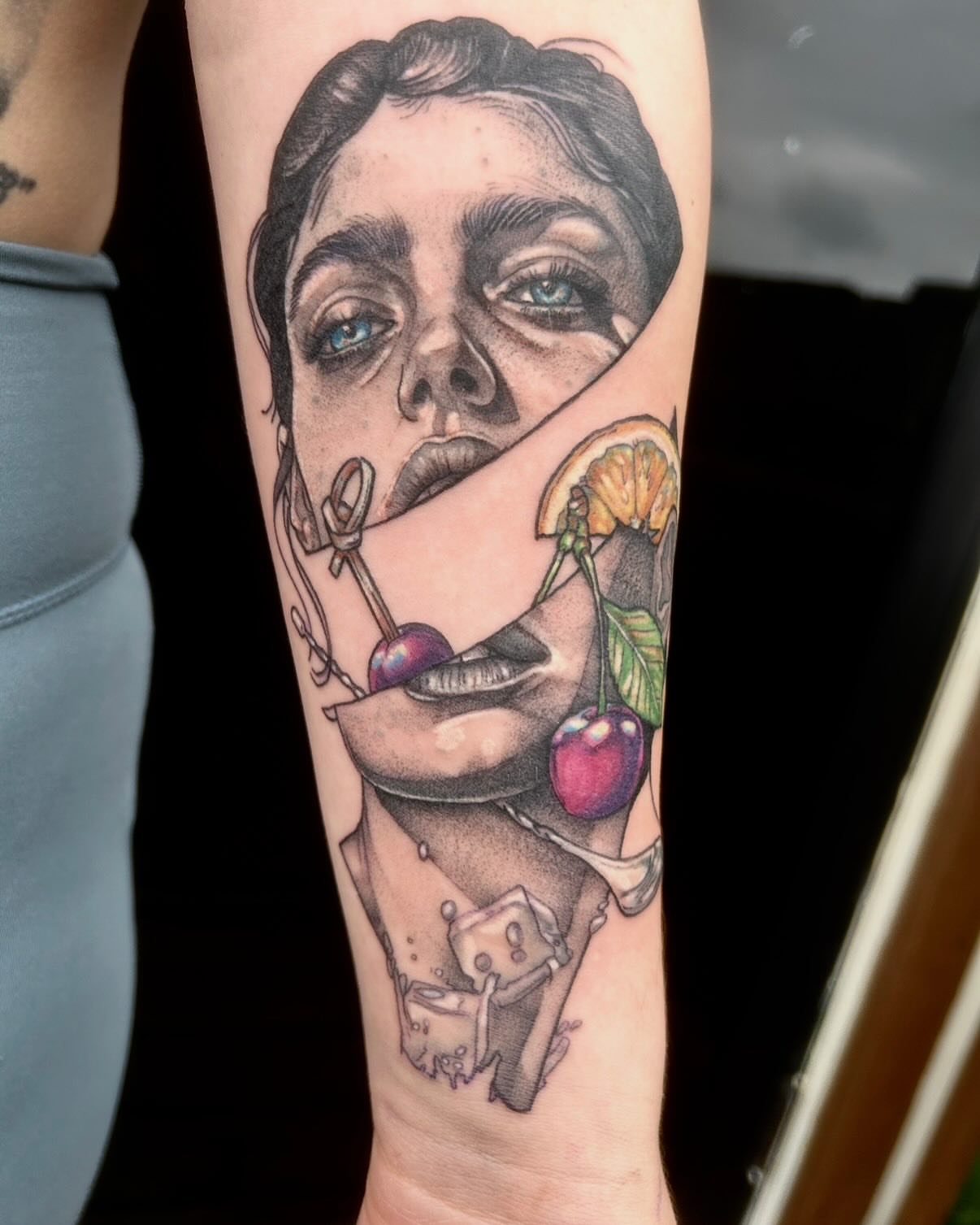 Woman's face with cherries realism tattoo on the forearm by Emily Falkowski
