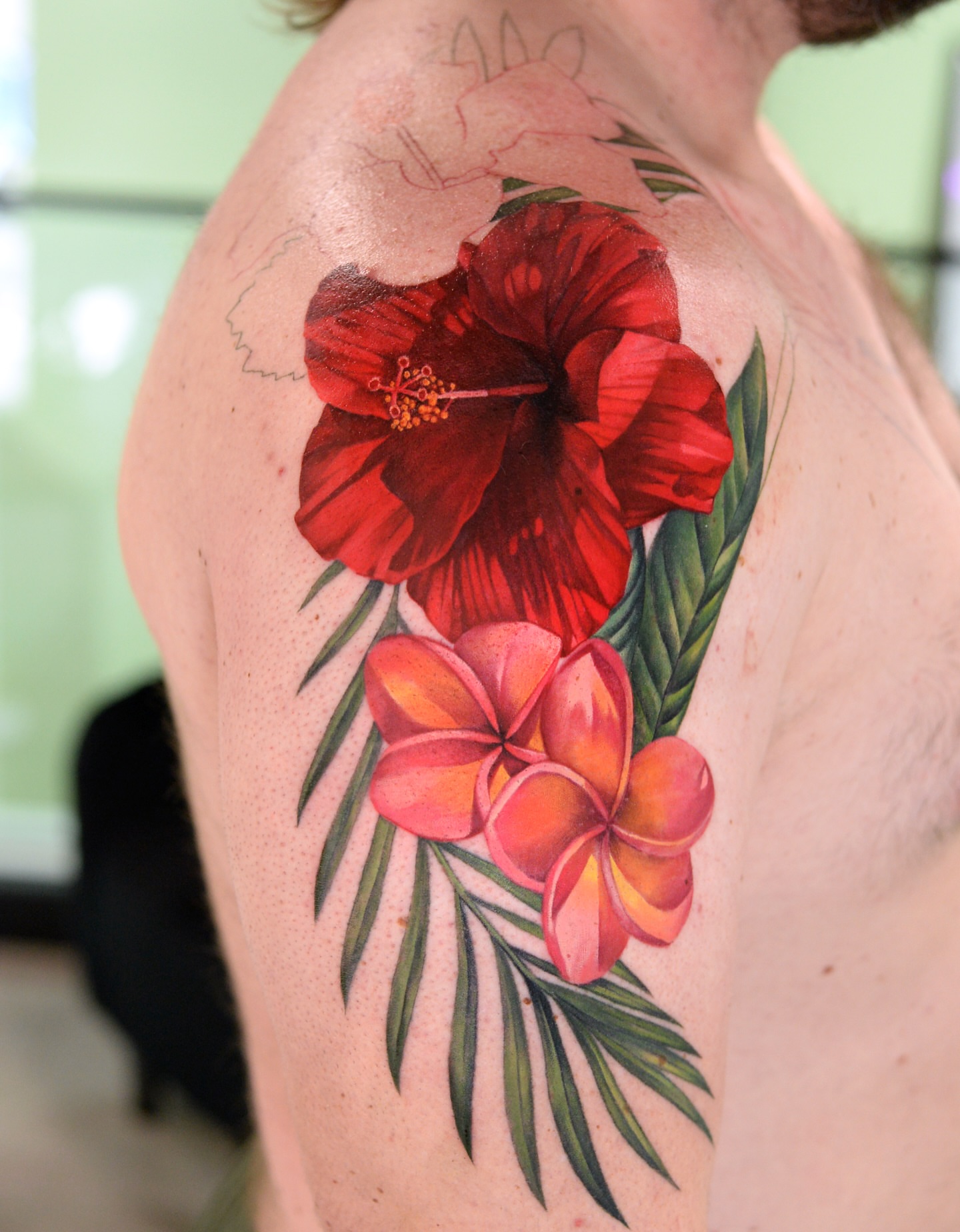 Red hibiscus and plumeria realism tattoo on the shoulder by Joice Wang