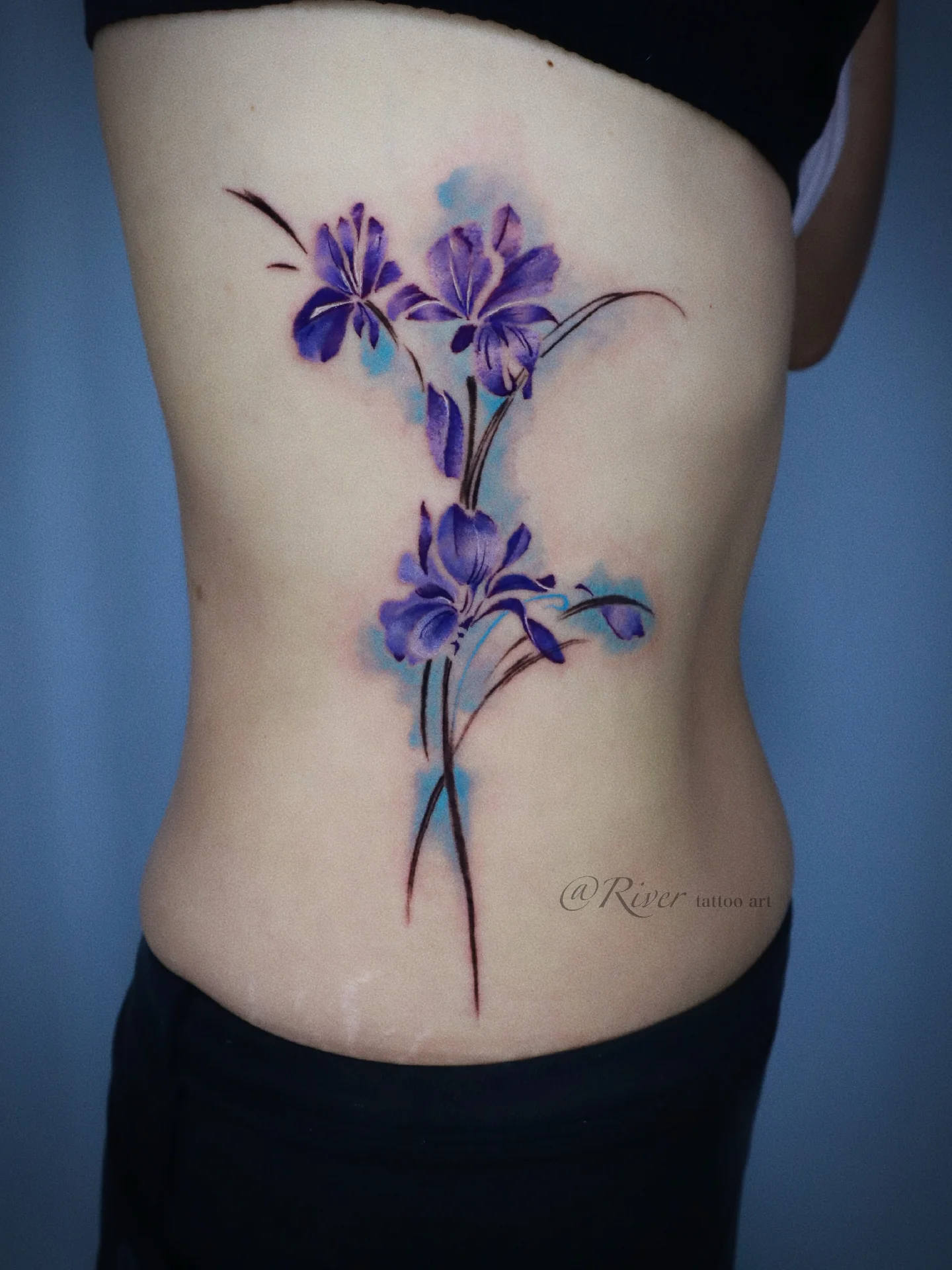 Purple flowers watercolor tattoo on the ribs by River