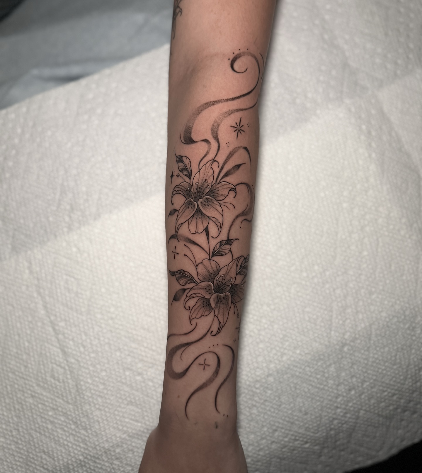 Lilies black and grey tattoo on the forearm by 𝕹𝖆𝖙