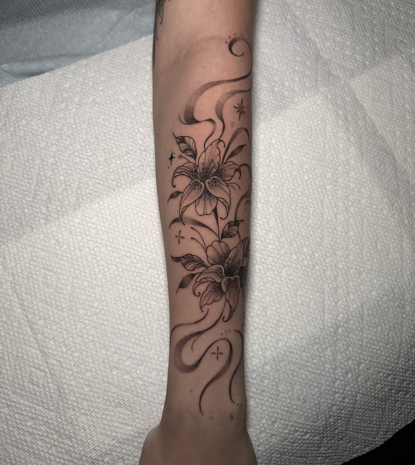 Lilies black and grey tattoo on the forearm by 𝕹𝖆𝖙