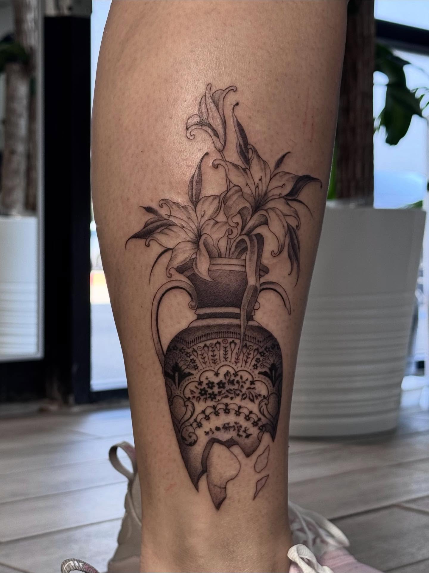 Vase with lilies black and grey tattoo on the calf by Nat🫧