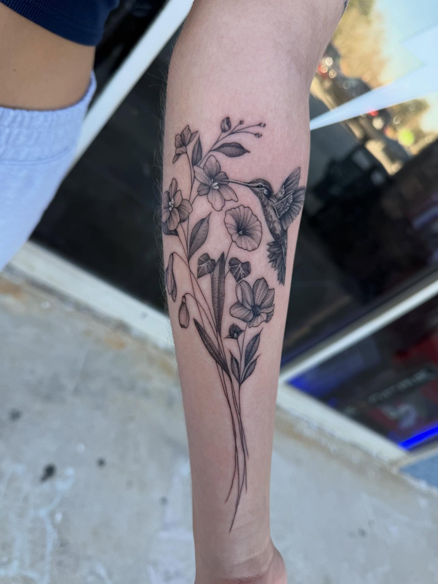Hummingbird and flowers black and grey tattoo on the forearm by Ashley matthews