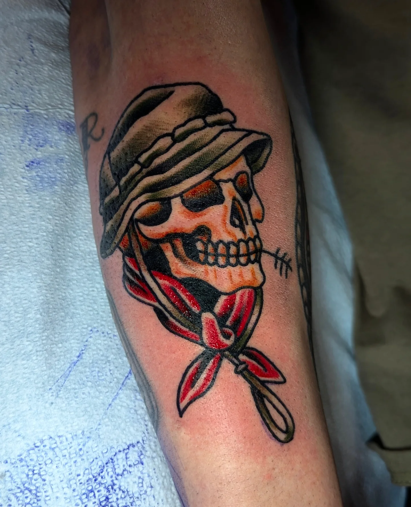 Skull wearing hat and bandana American traditional tattoo on the forearm by Eric Ward