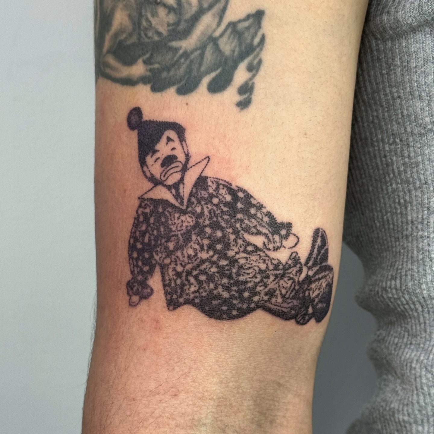 Clown black and grey tattoo on the forearm by Joint Killer