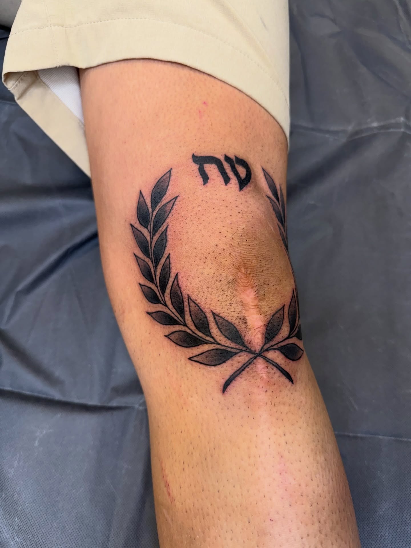 Wreath and Hebrew letters black and grey tattoo on the forearm by Ricky Sanchez, Duncanville, Texas