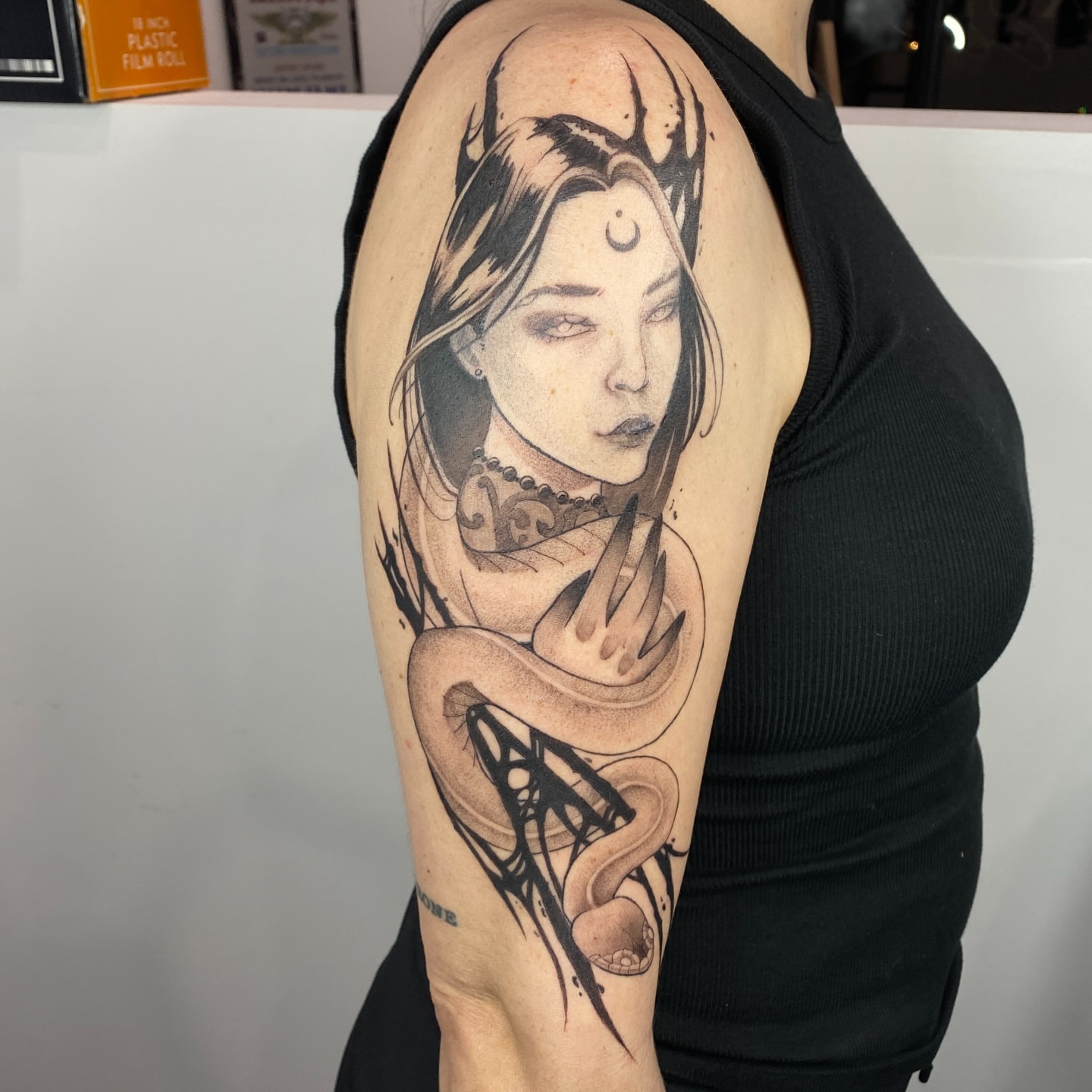 Woman with snake realism tattoo on the upper arm by Nikole