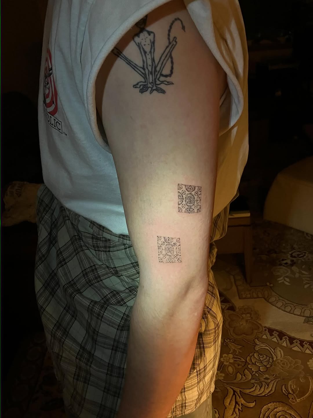 Ornamental square patterns and abstract figure minimalist tattoo on the forearm by Sashka