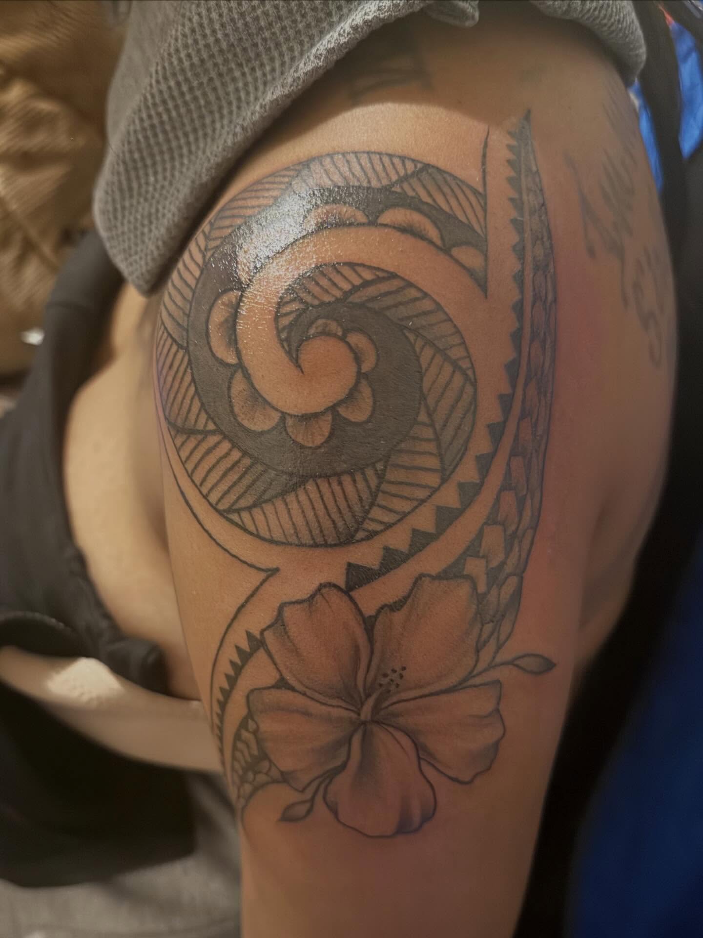 Hawaiian flower and spiral tribal tattoo on the shoulder by Aja Marie