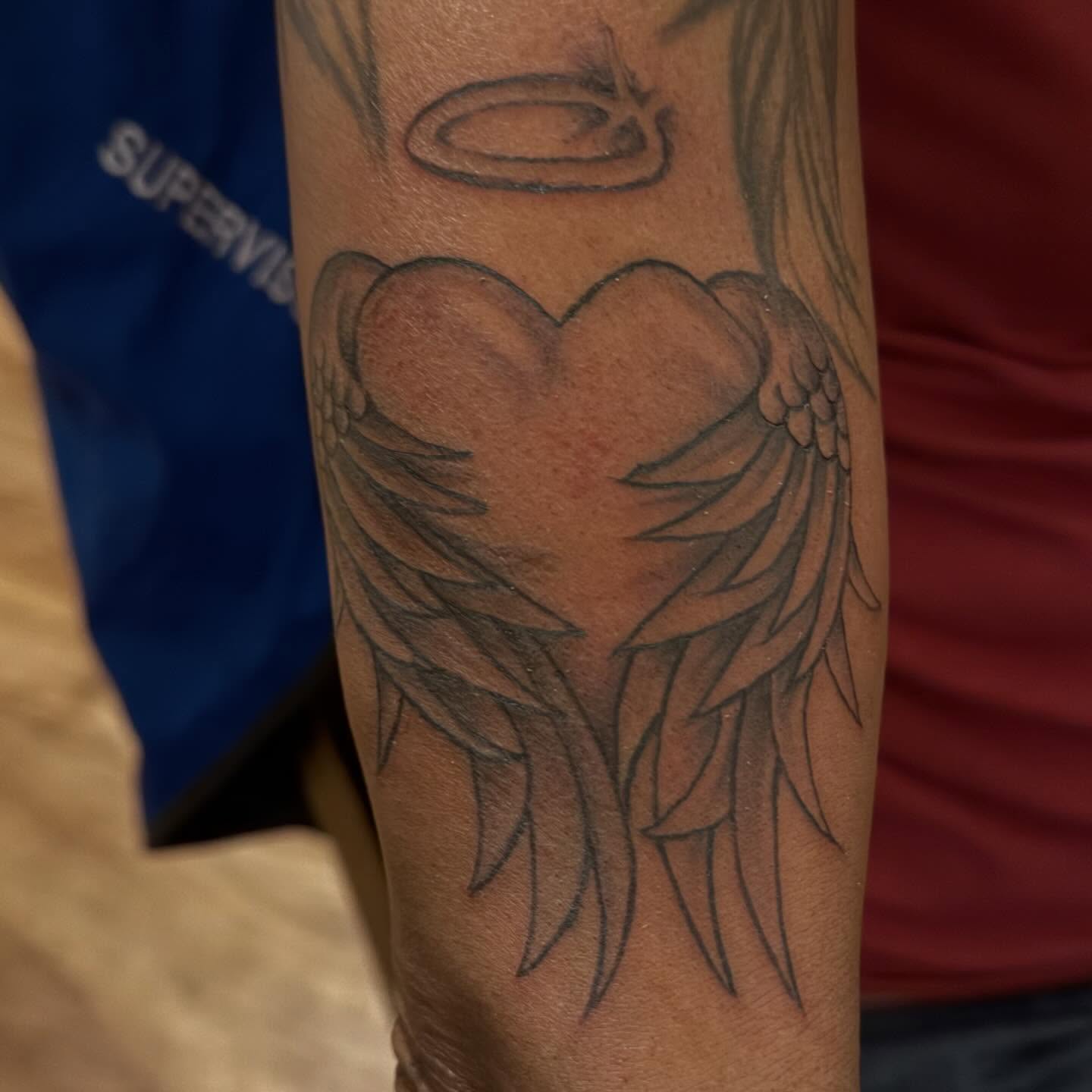 Heart with wings black and grey tattoo on the forearm by Aja Marie