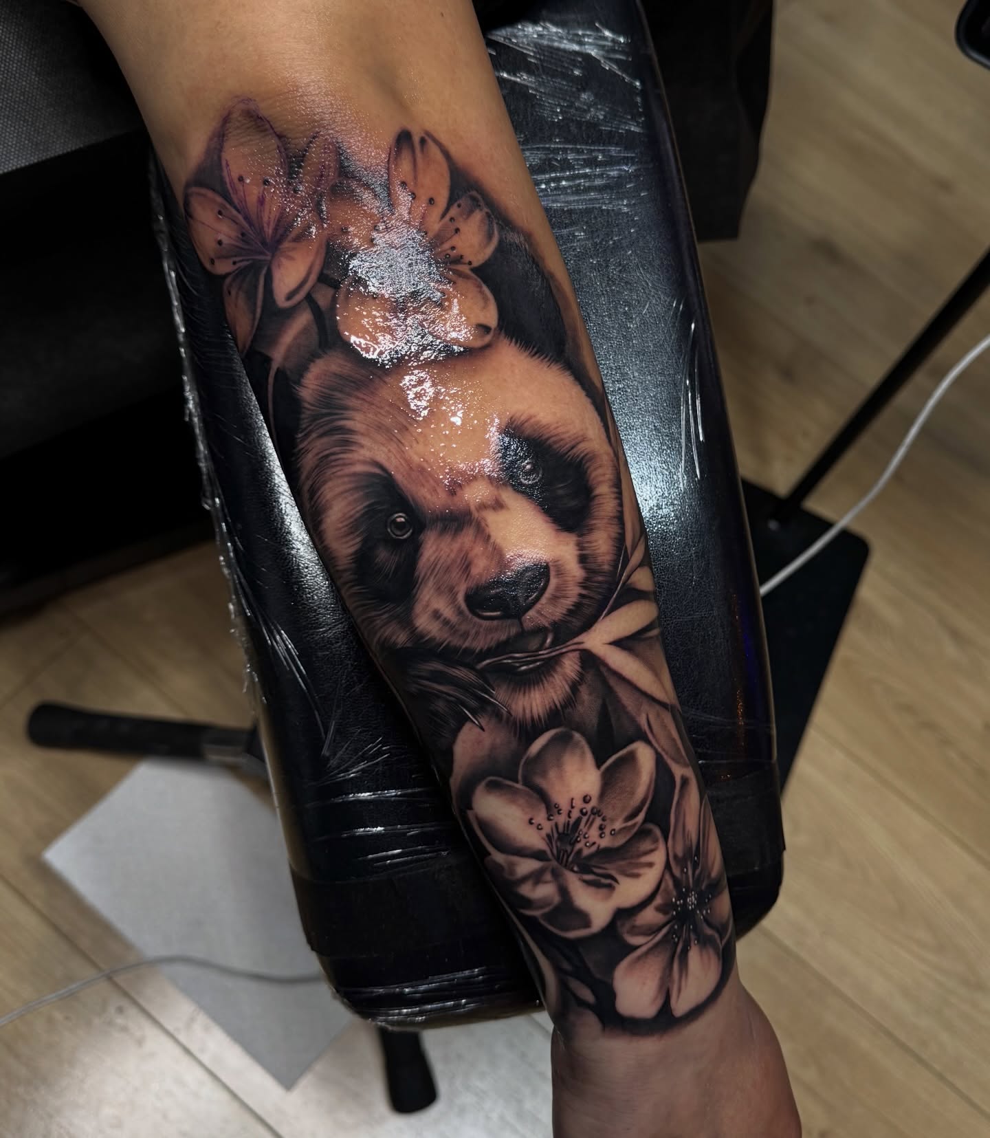 Bear and flowers realism tattoo on the forearm by Flamure Islami