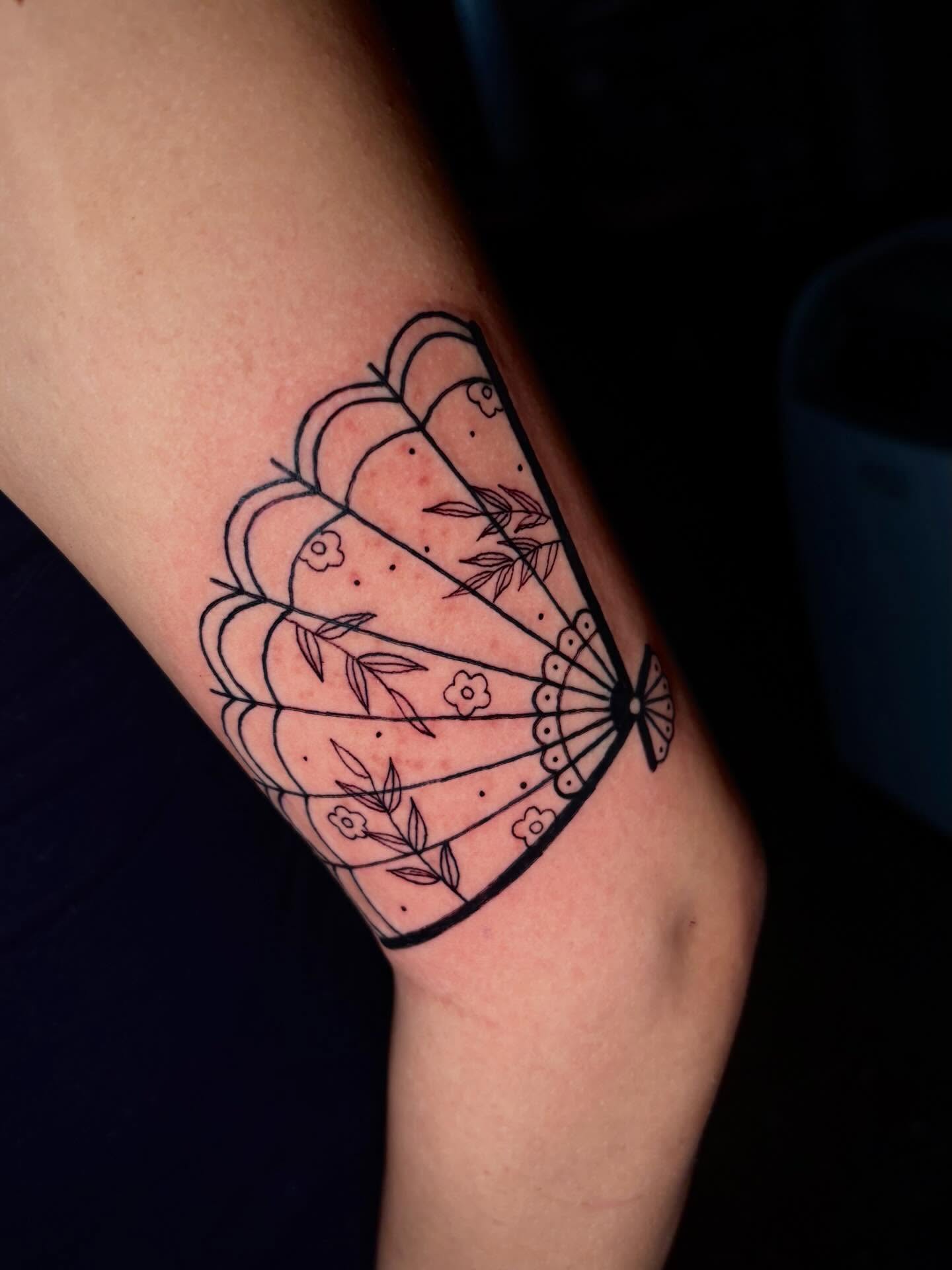 Fan fine line tattoo on the forearm by Jenna Clayton