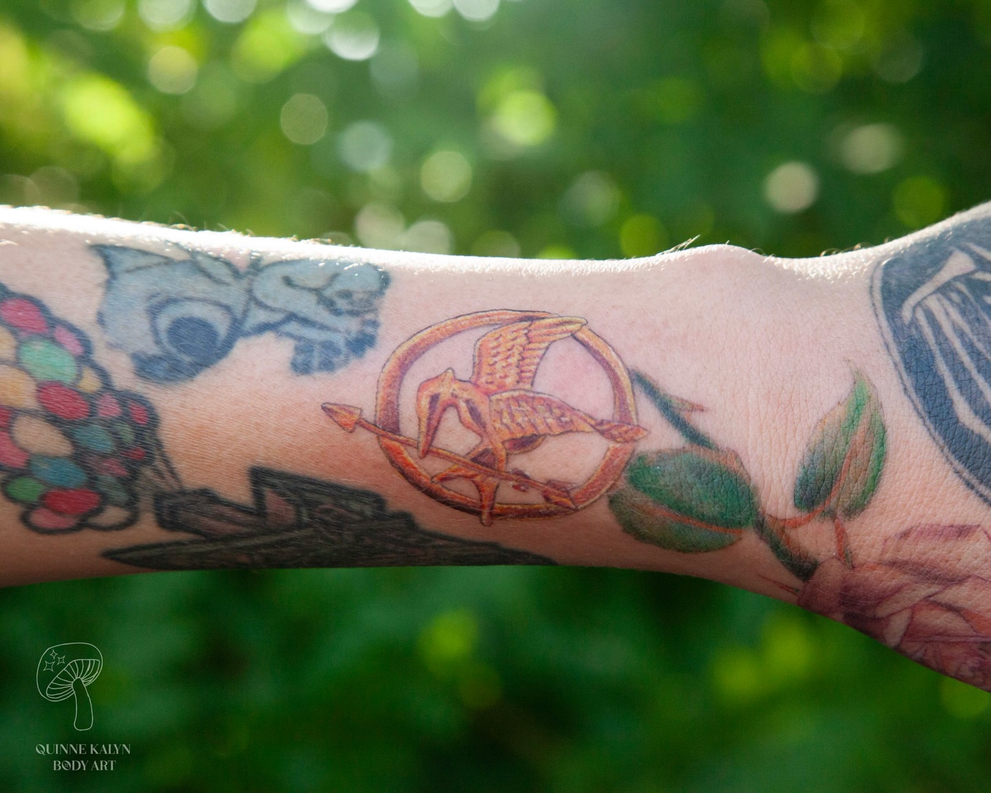 Hunger games mockingjay pin neo-traditional tattoo on the forearm by Nashville Piercer & Tattoo Artist ✨ Quinne