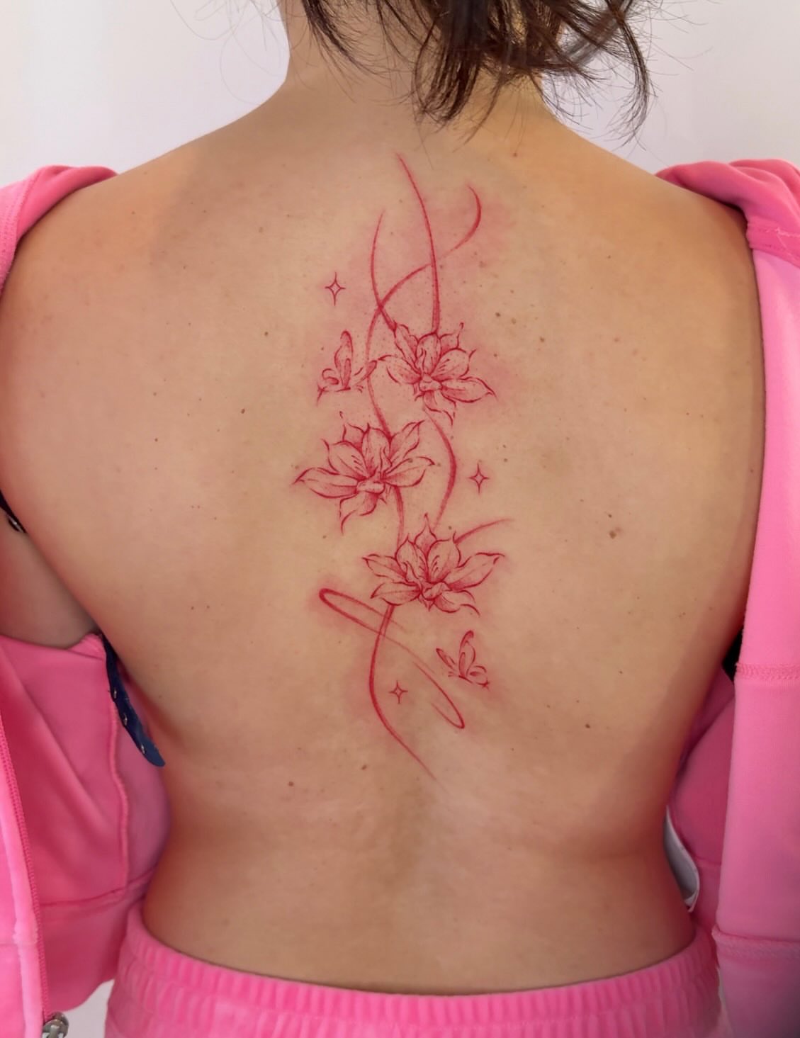 Flowers and butterflies fine line tattoo on the back by Ethan