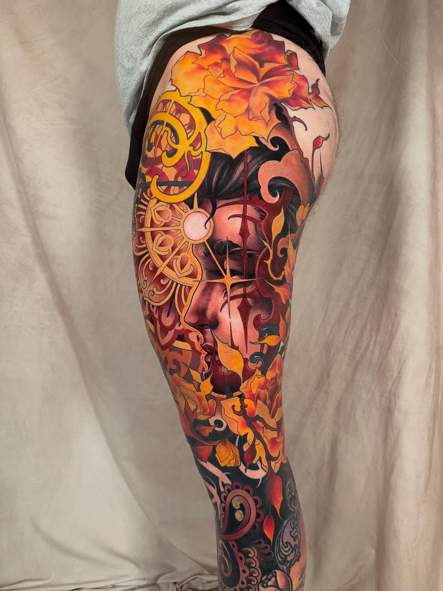 Abstract face with floral elements illustrative tattoo on the thigh by <