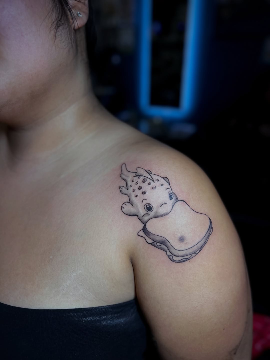Cartoon creature eating a sandwich new school tattoo on the shoulder by Dani Sandoval, Anaheim, California