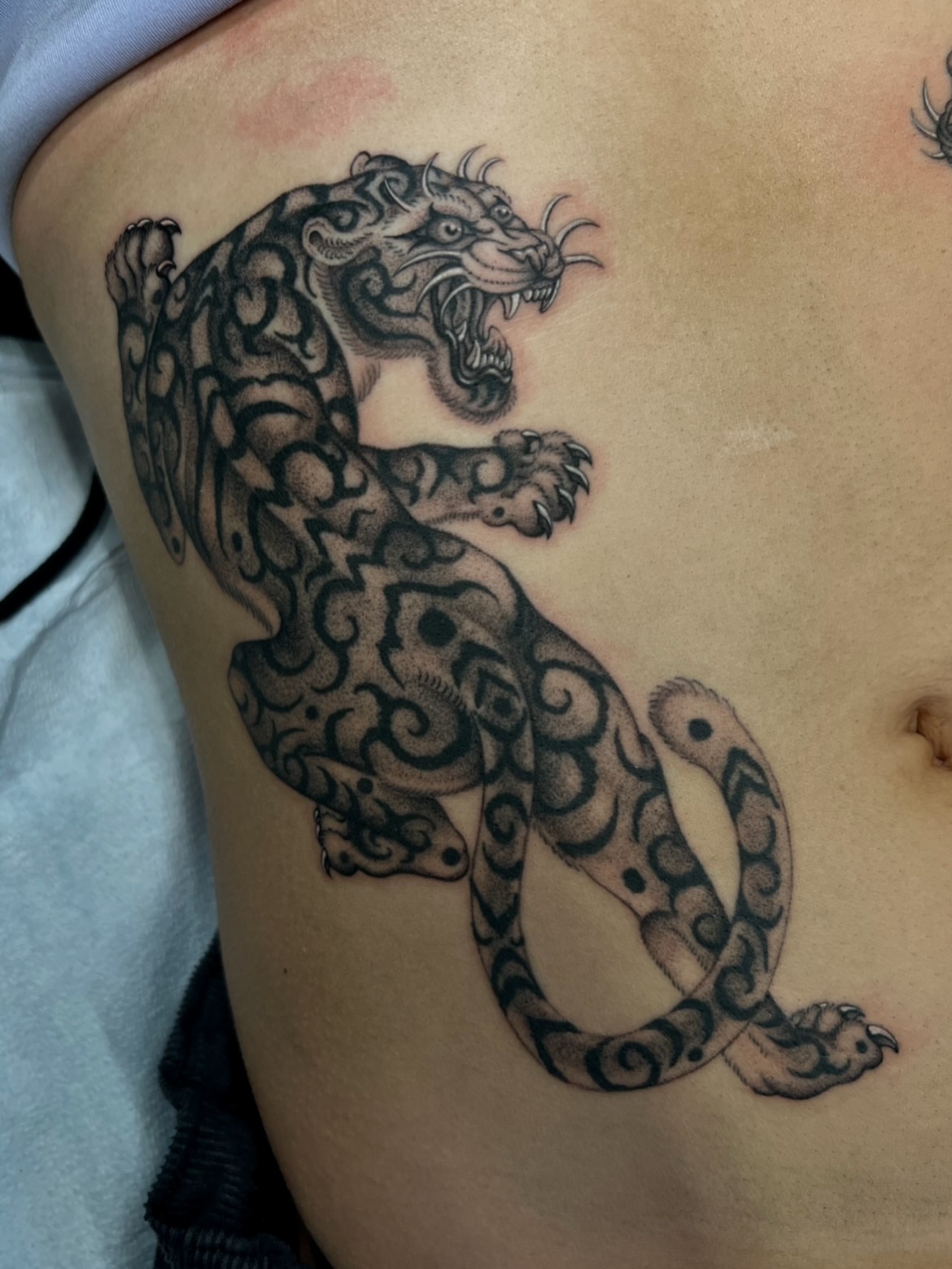 Roaring panther black and grey tattoo on the thigh by Cassidy Maples