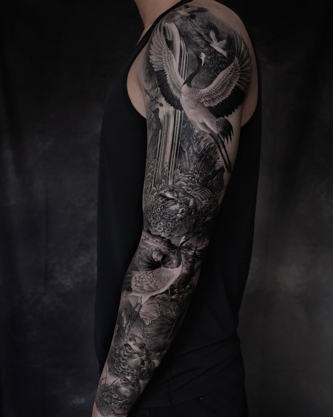 Cranes and frogs in a landscape Japanese tattoo on the forearm by Xin Wang