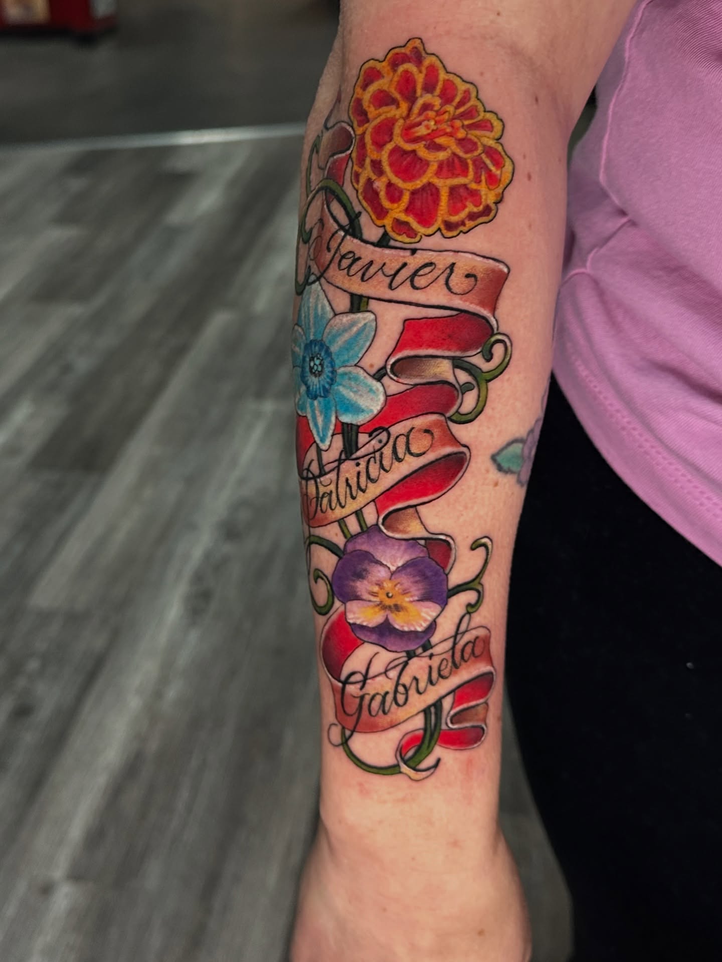 Flower and ribbon American traditional tattoo on the forearm by Skoty Fox