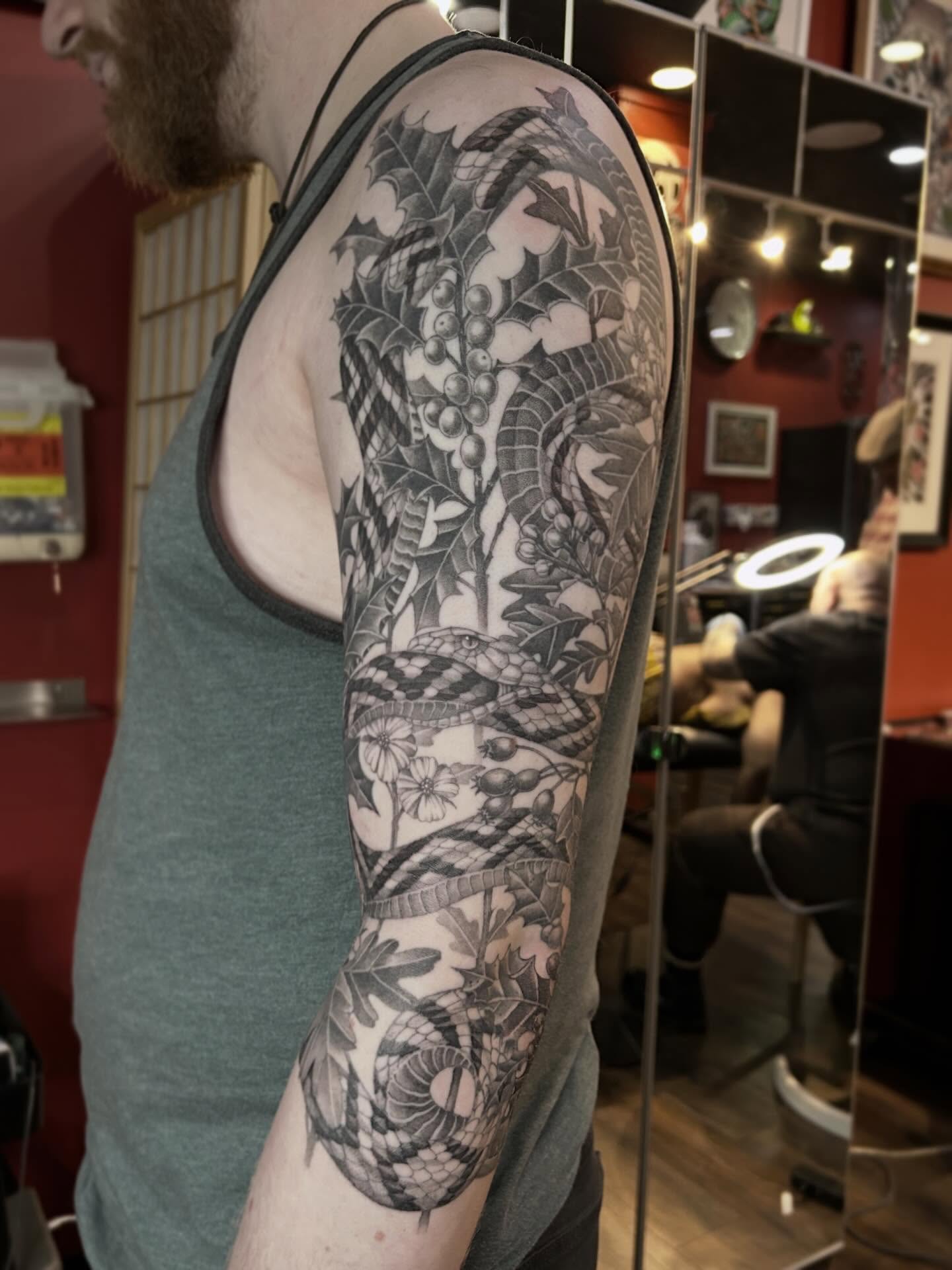 Snake and leaves realism tattoo on the upper arm by Tako, Seattle, Washington