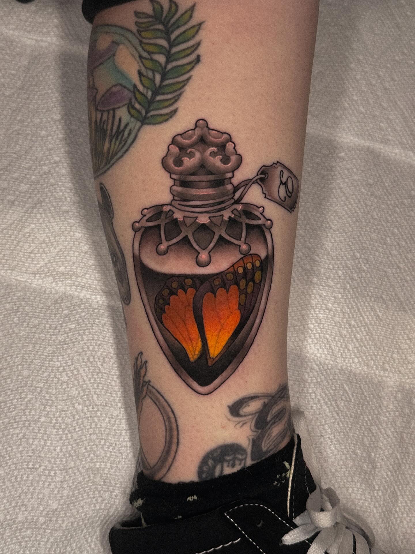Heart-shaped perfume bottle geometric tattoo on the forearm by Nathan Thomas