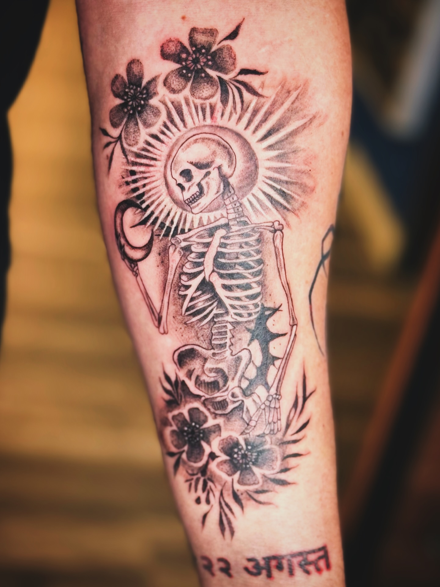 Skeleton with flowers black and grey tattoo on the forearm by Kate