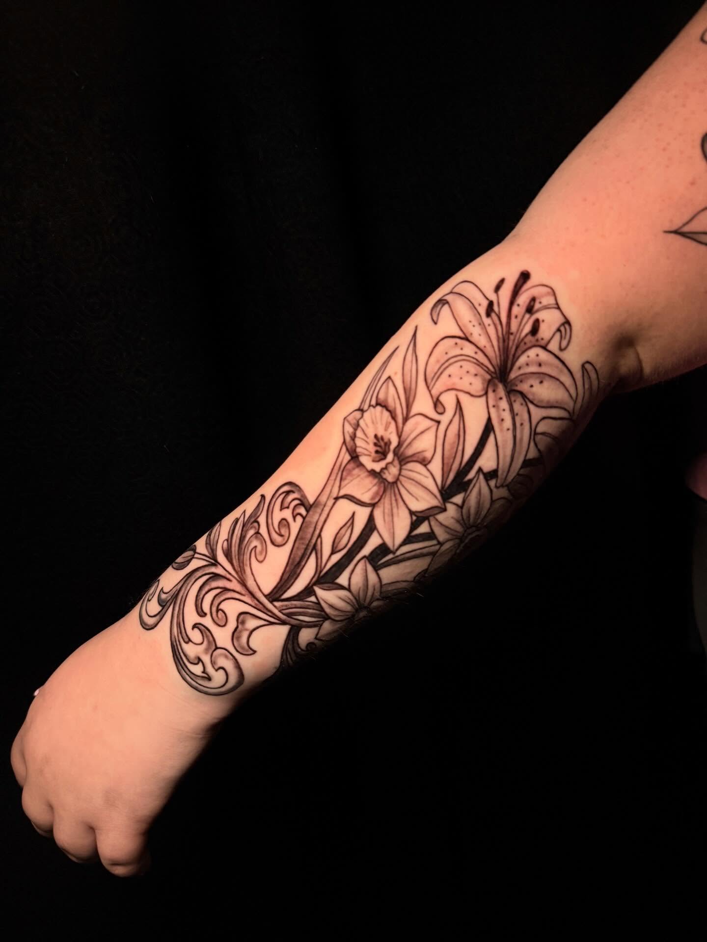 Lilies and floral patterns black and grey tattoo on the forearm by Nicholas A. Estes-Davis