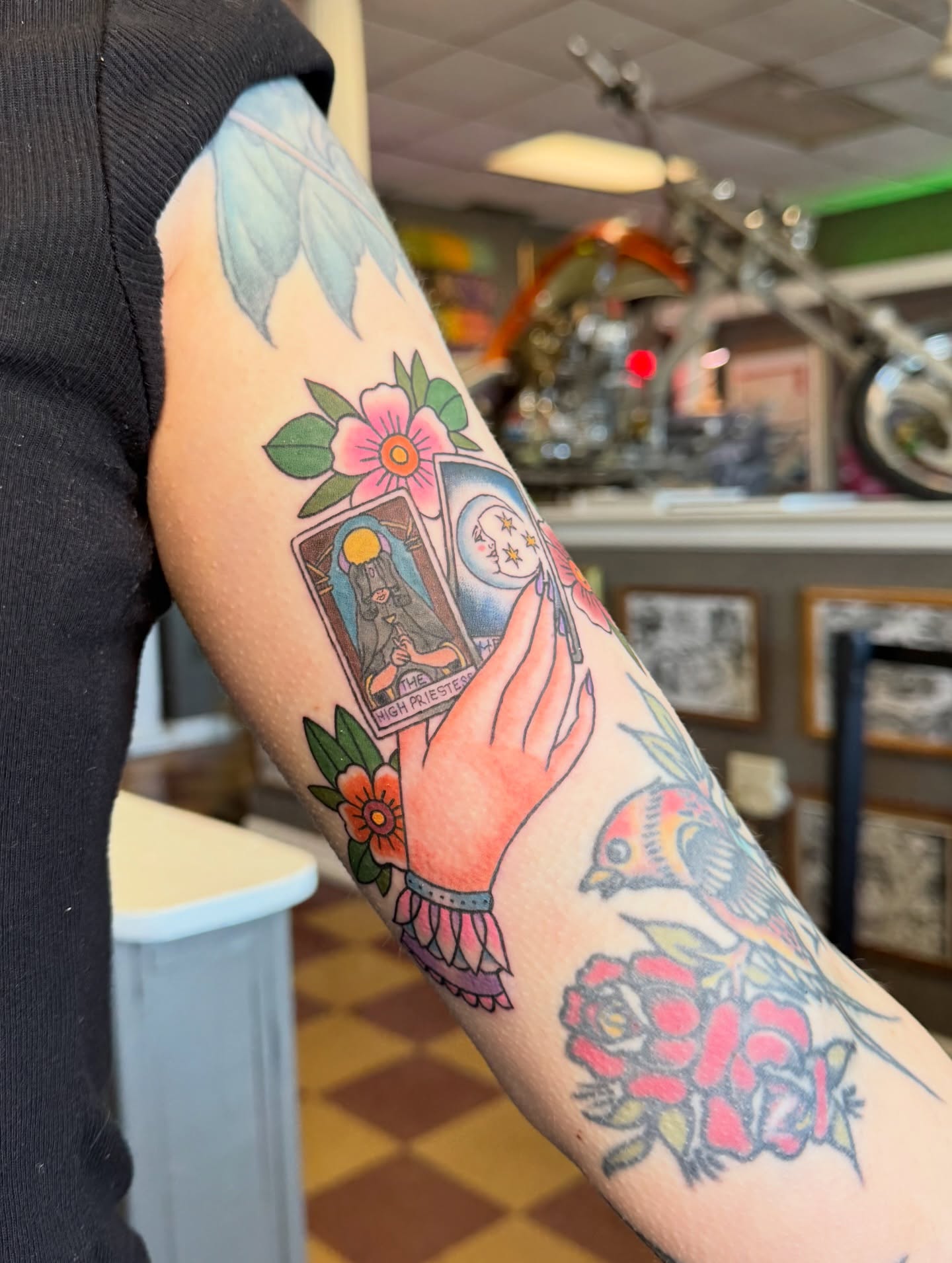 Tarot card and floral American traditional tattoo on the forearm by Cora Phelps