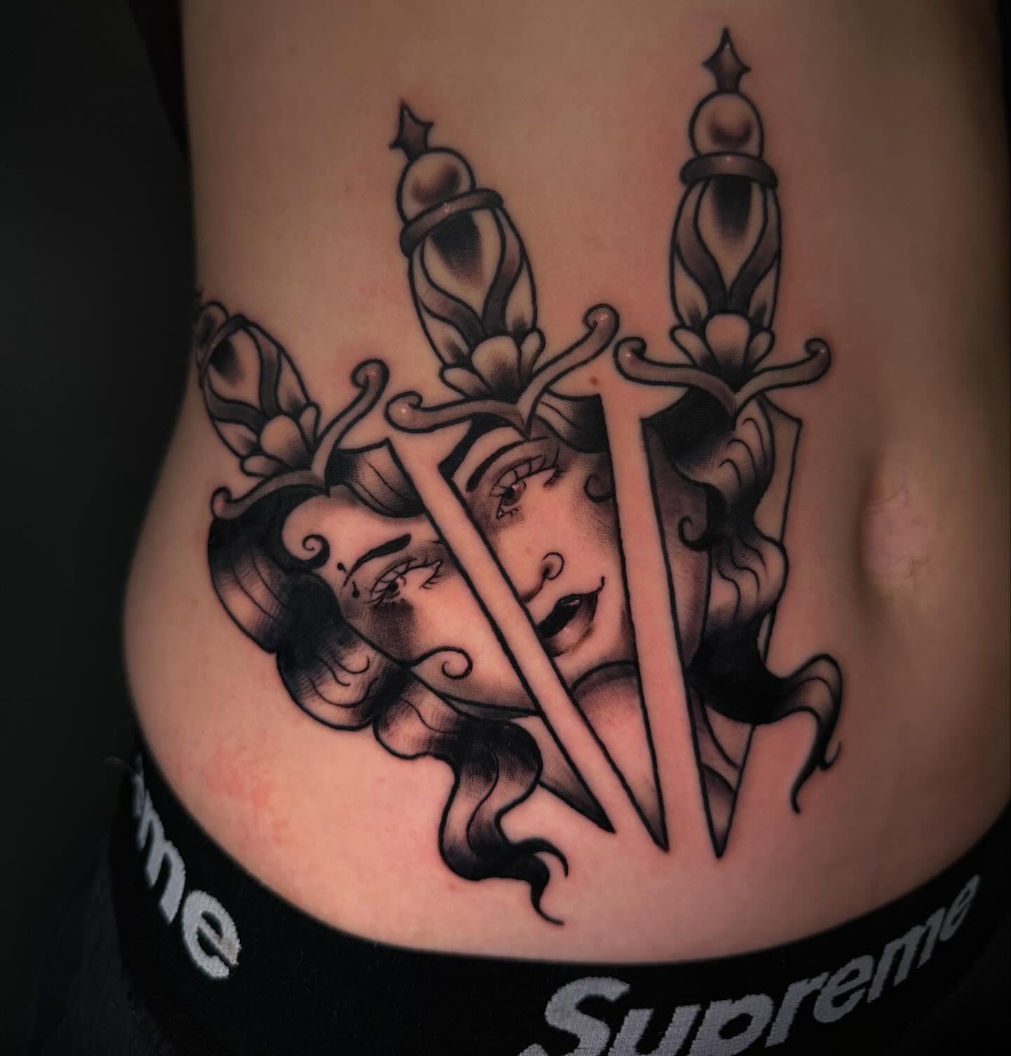 Woman's face with swords American traditional tattoo on the torso by Kodi Green