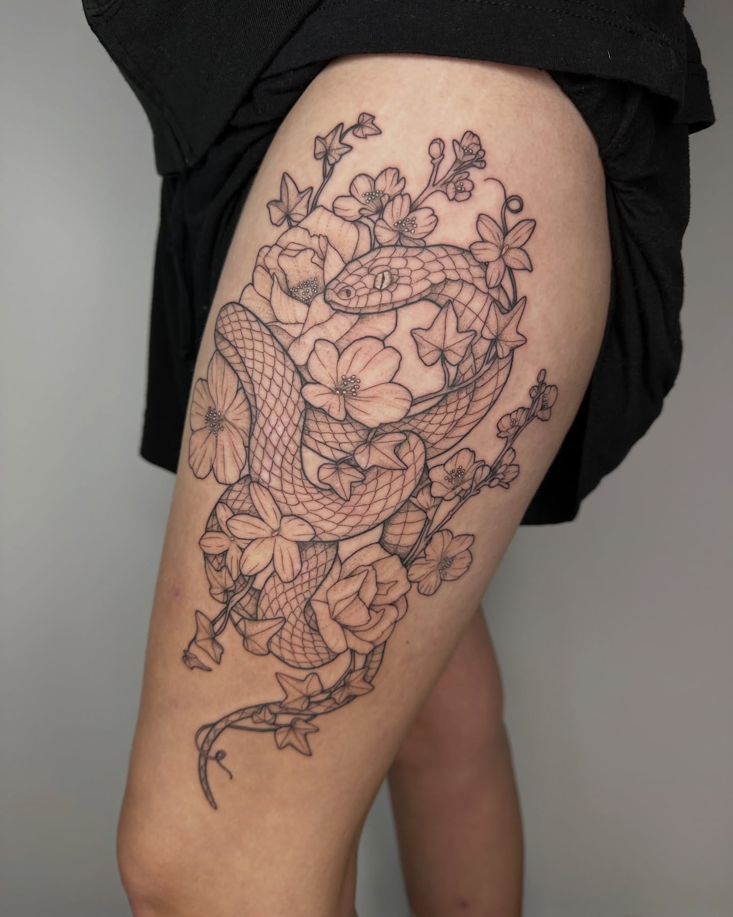 Snake and flowers realism tattoo on the thigh by PenumbRaeTattoo
