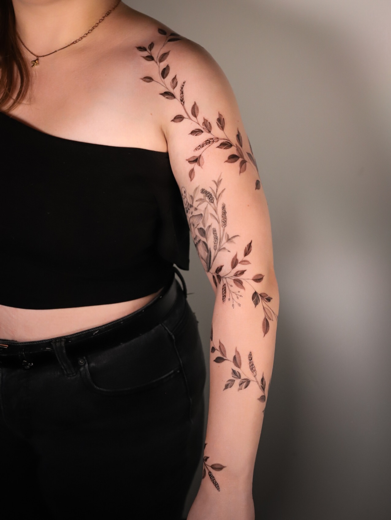 Botanical black and grey tattoo on the upper arm by Cyn