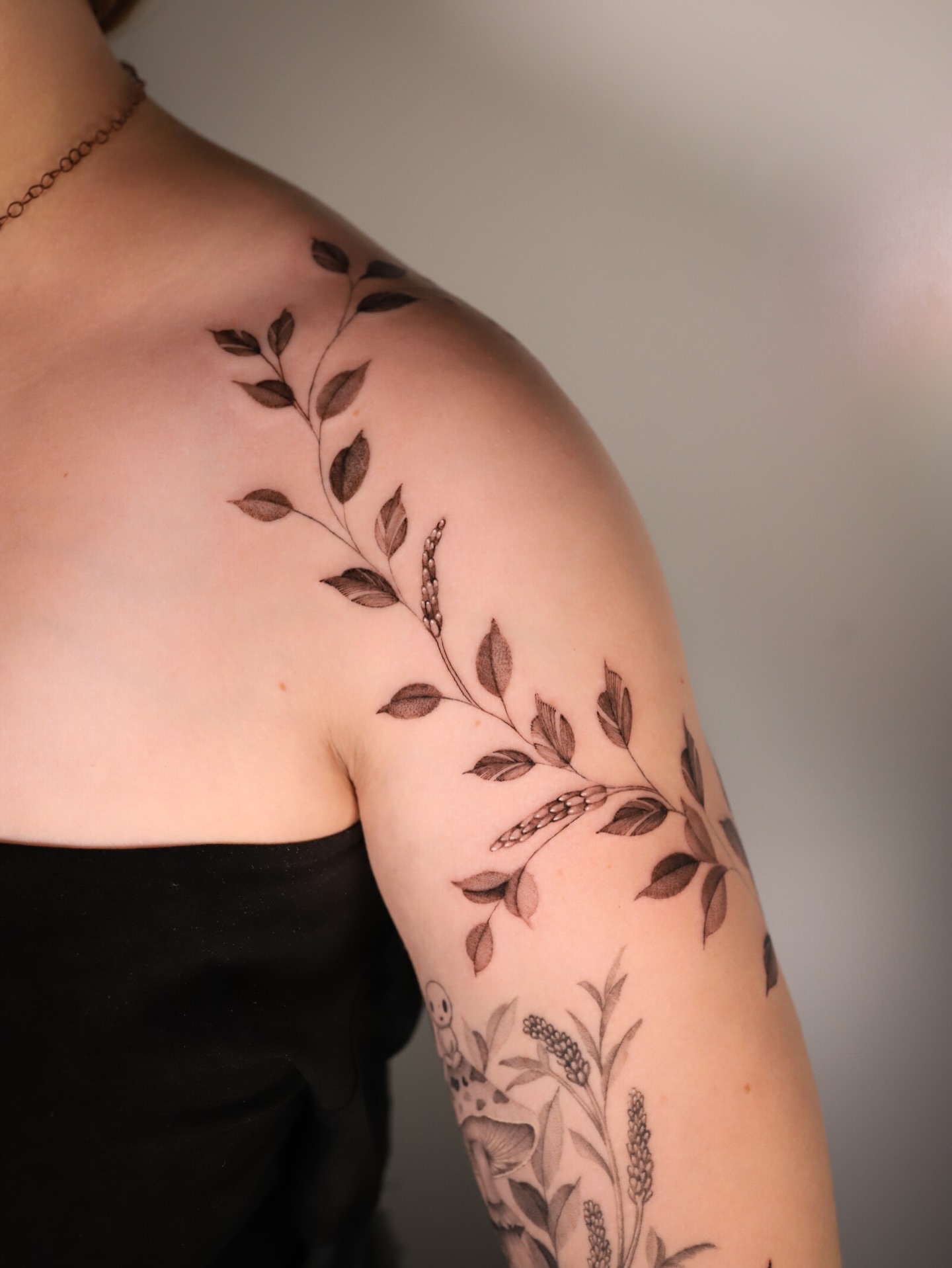 Branch with leaves black and grey tattoo on the upper arm by Cyn