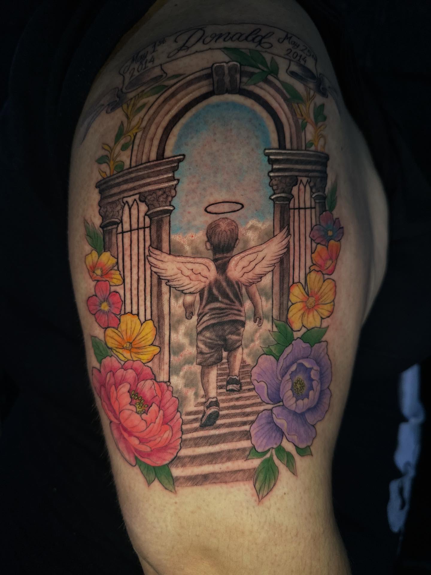 Child with wings ascending illustrative tattoo on the upper arm by Mario Flores Tattoo