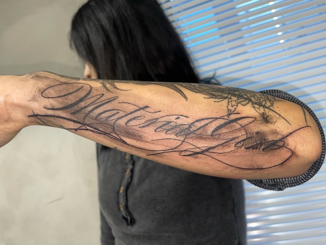 Script lettering with smoke effect lettering tattoo on the forearm by eyeball