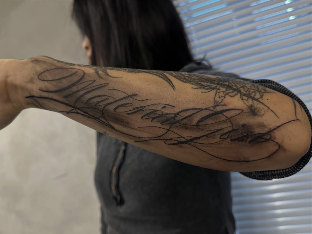Script lettering with feather lettering tattoo on the forearm by eyeball
