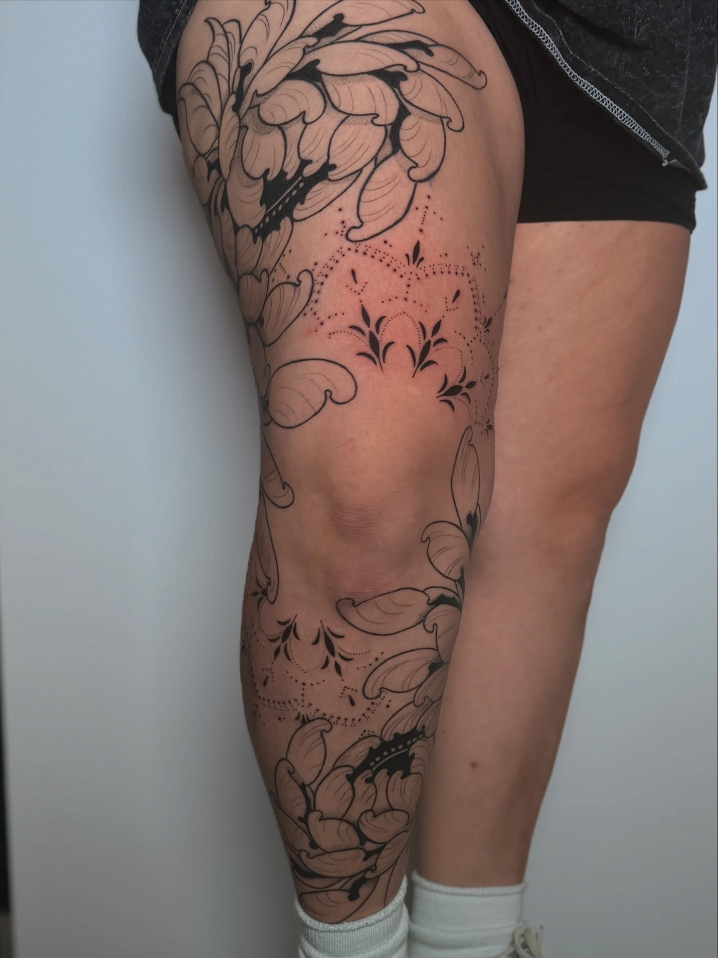 Floral design black and grey tattoo on the thigh by Rachel