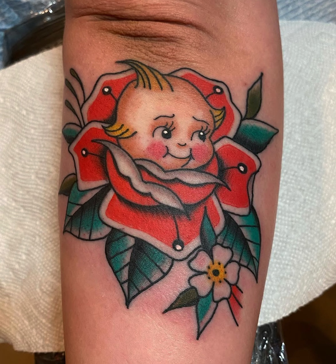Baby surrounded by roses American traditional tattoo on the forearm by atomlenhart, Lancaster, Pennsylvania
