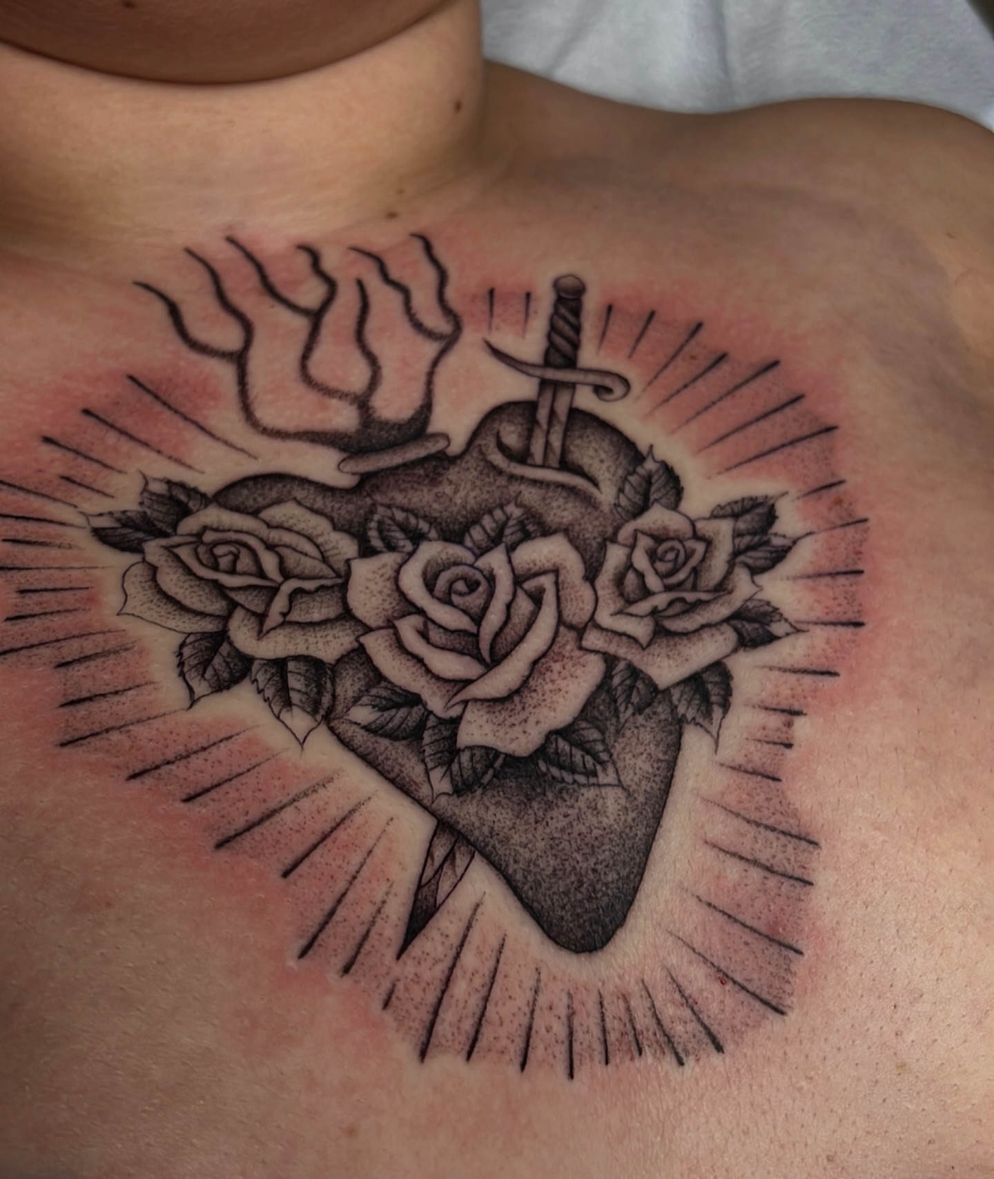 Heart with roses and dagger American traditional tattoo on the chest by David Delacruz