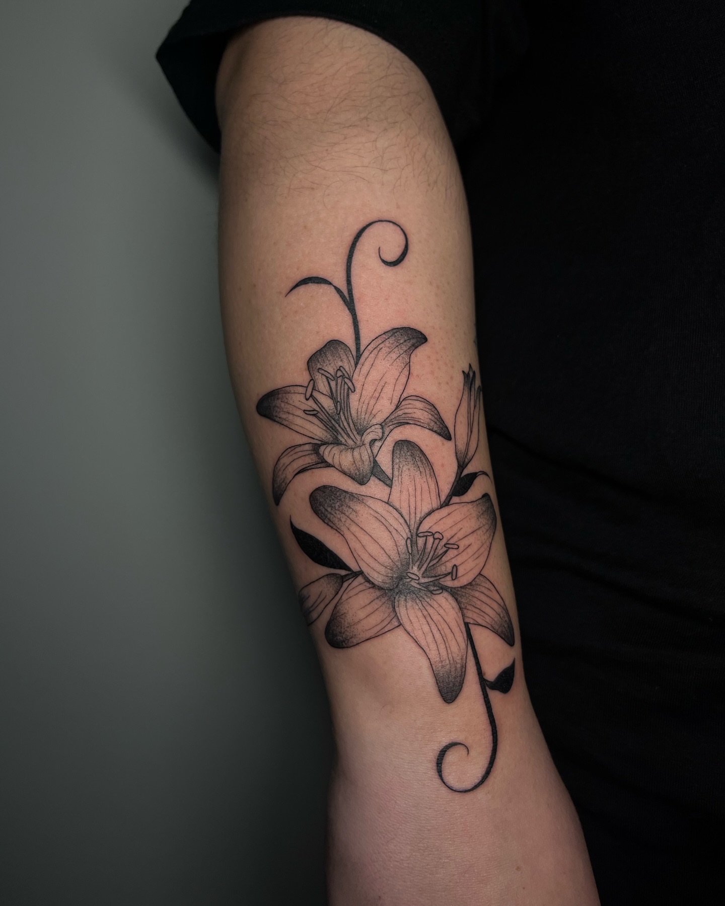 Lilies black and grey tattoo on the forearm by Daniela