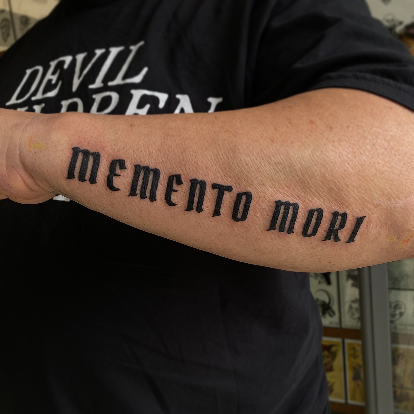 Memento mori lettering script tattoo on the forearm by Corinne Carter