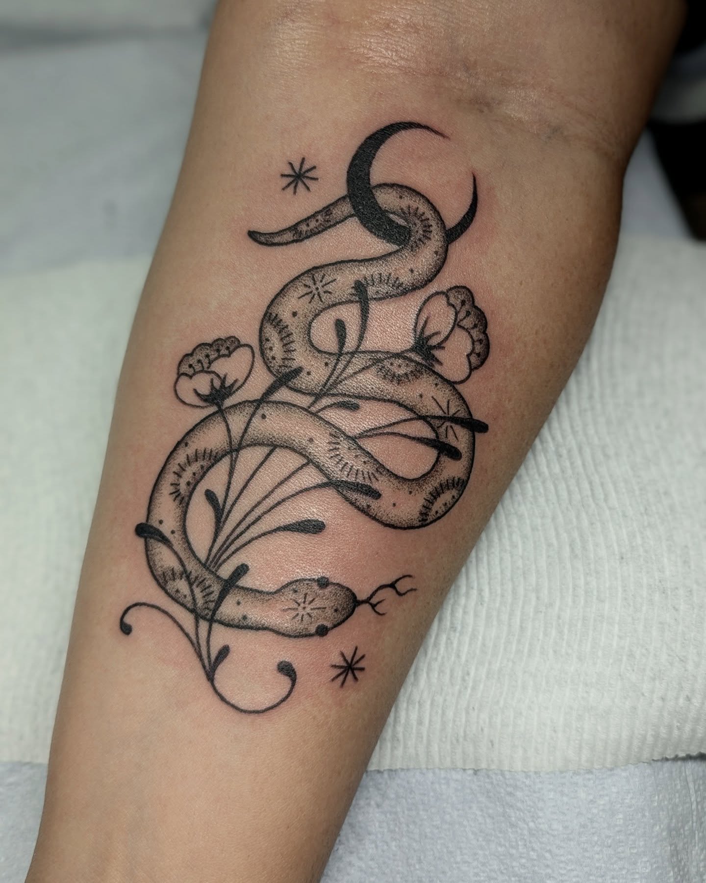 Snake and flowers dotwork tattoo on the forearm by Dani Harkey