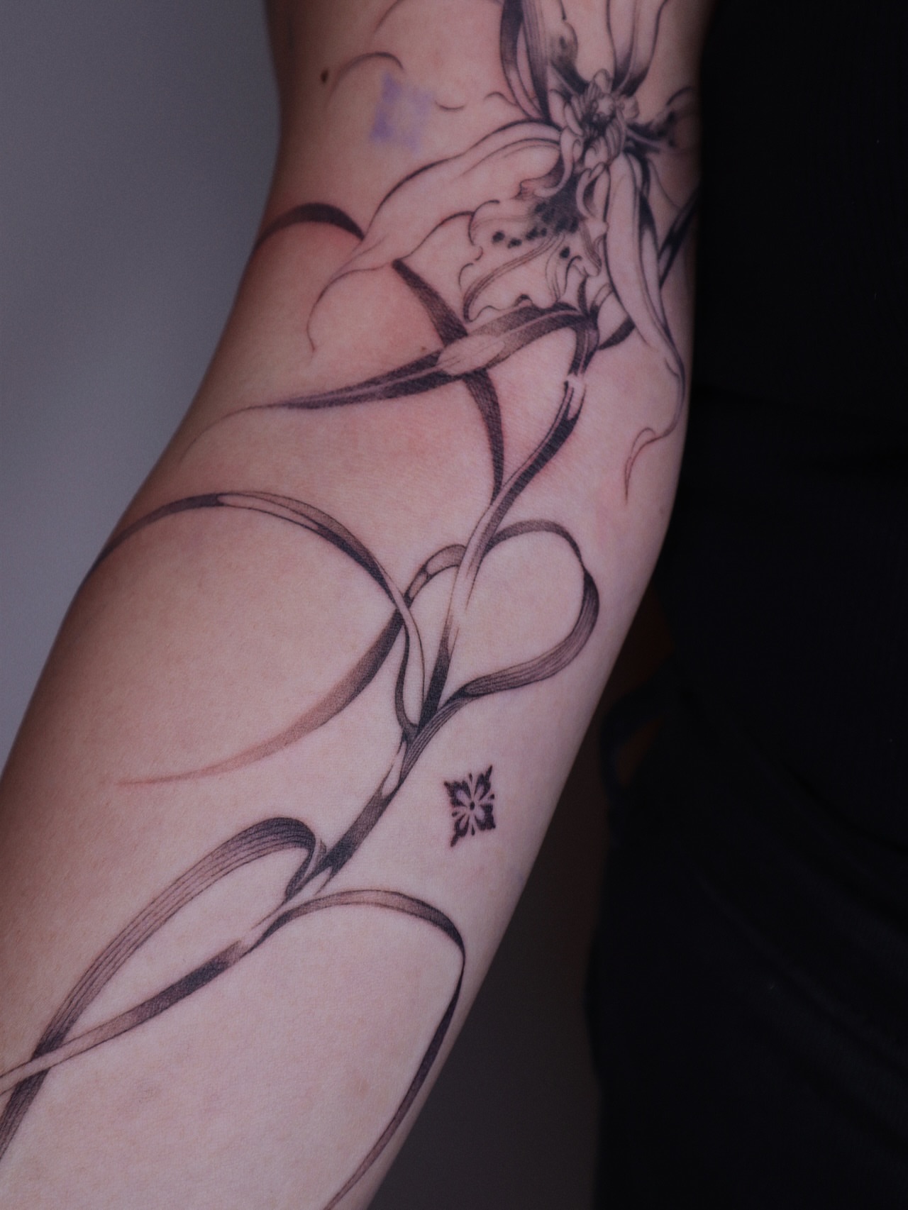 String and flower black and grey tattoo on the forearm by Savana Wang