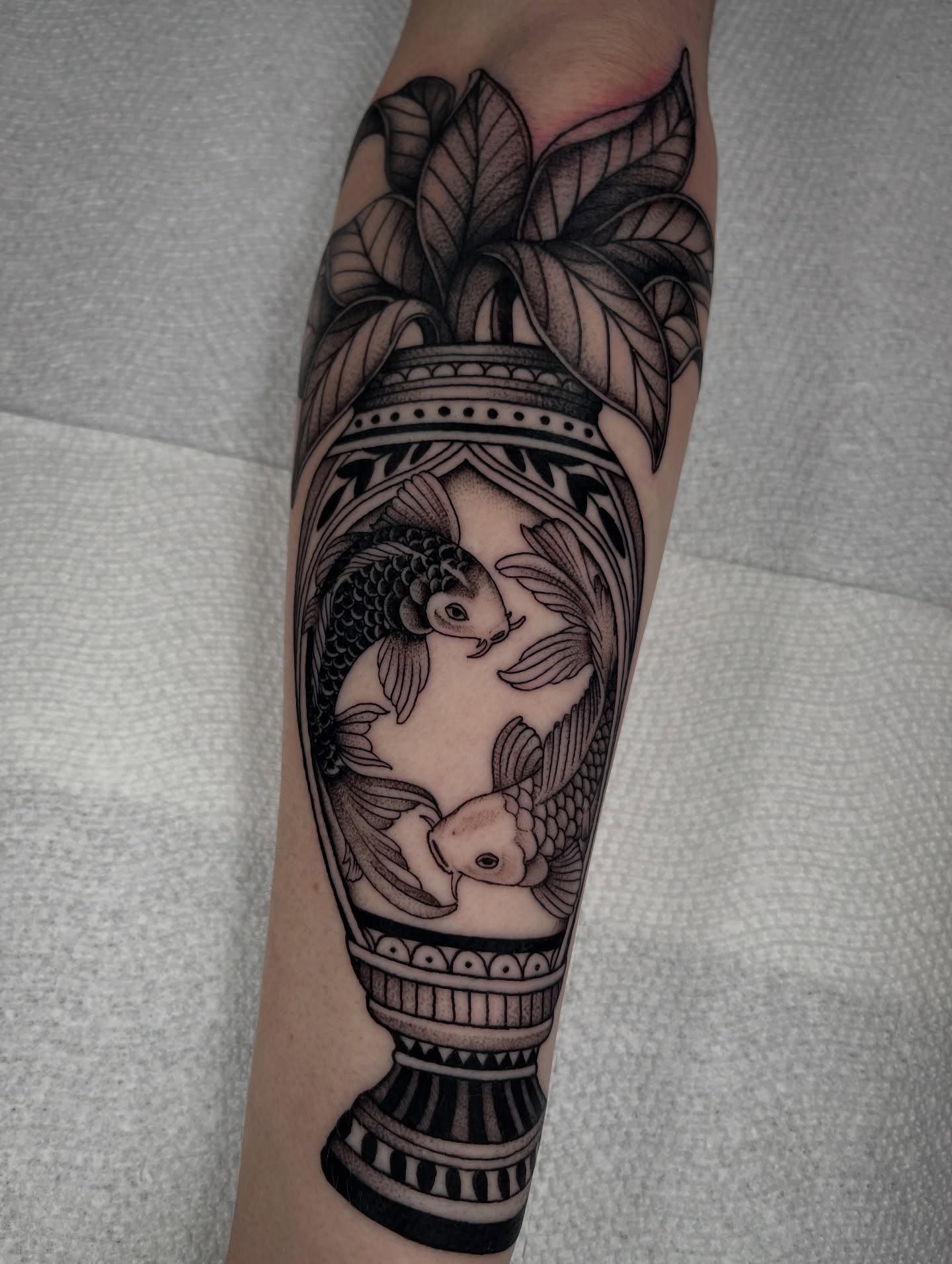 Koi fish in vase black and grey tattoo on the forearm by Jordan Hunt