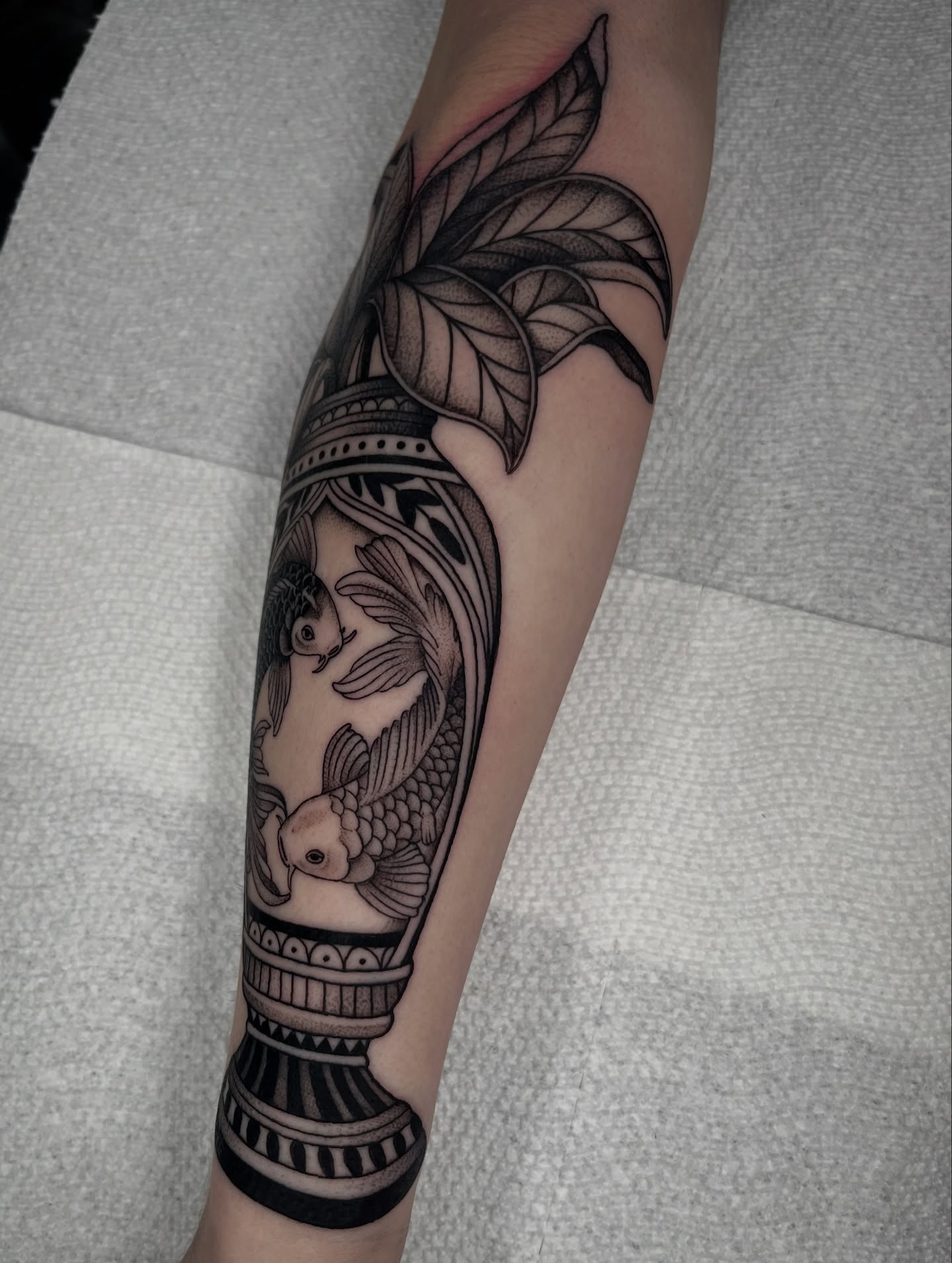 Koi fish and lotus realism tattoo on the forearm by Jordan Hunt