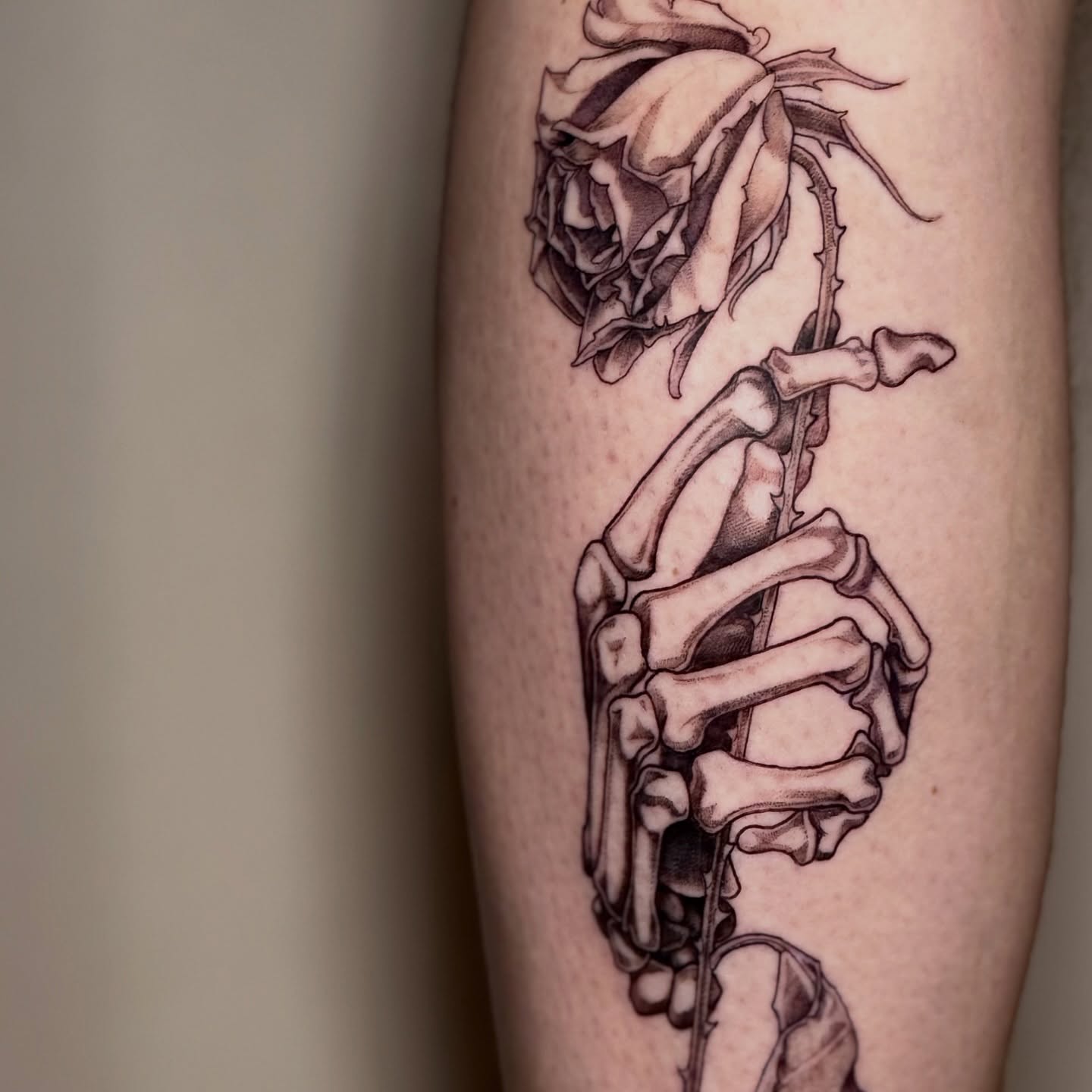 Skeleton holding rose realism tattoo on the forearm by Lydia Jude