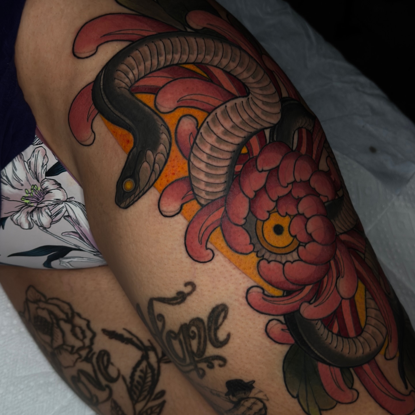 Snake and peony American traditional tattoo on the upper arm by Golden Heart Tattoo Co