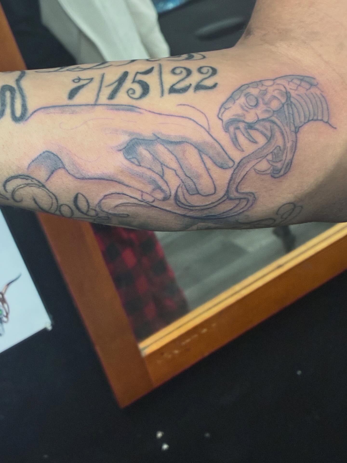 Snake and hand black and grey tattoo on the forearm by Trae