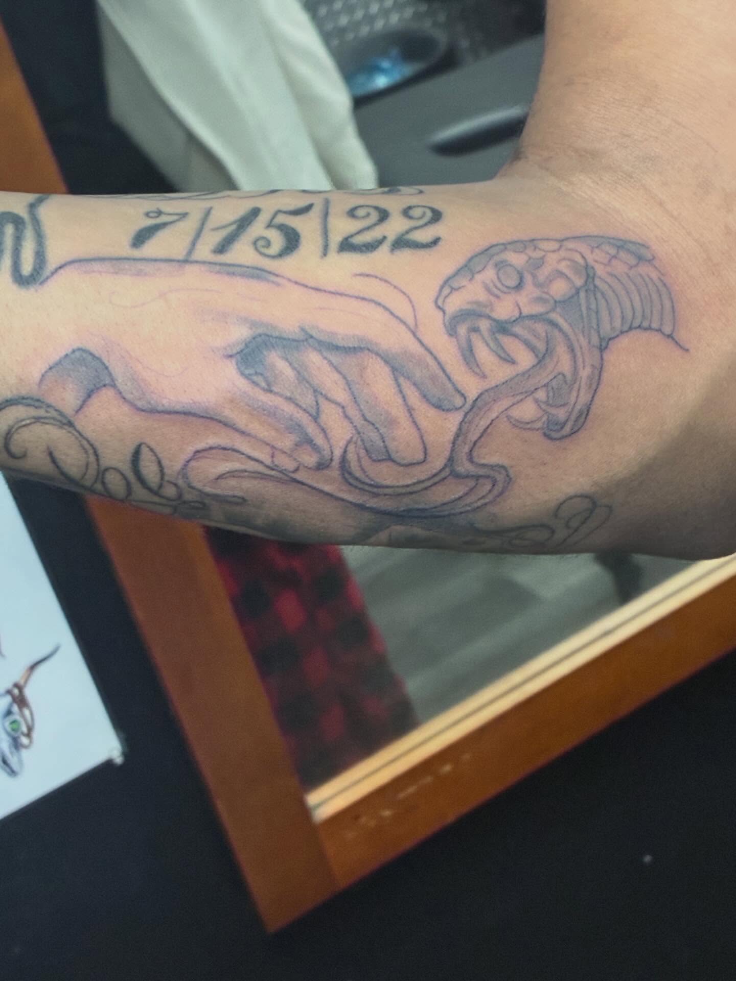 Snake and hand black and grey tattoo on the forearm by Trae