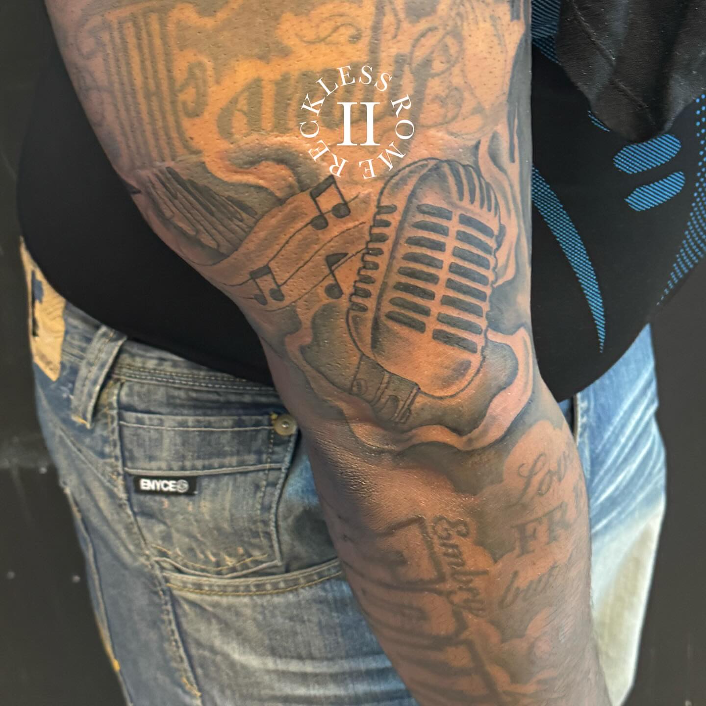 Microphone and musical notes black and grey tattoo on the forearm by Rome